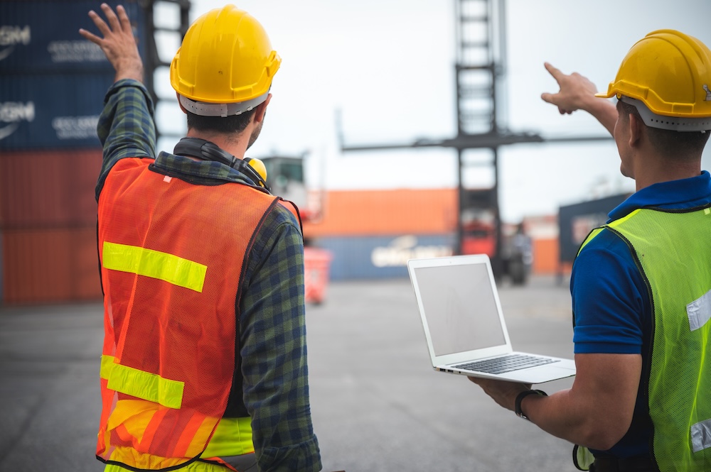 Foreman engineer working in container yard, Quality control Inspector using laptop for checking on container site, logistic store for import and export concept